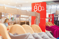 Rack of clothing in retail store with sale sign