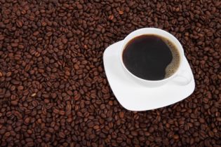 Cup of coffee on coffee beans